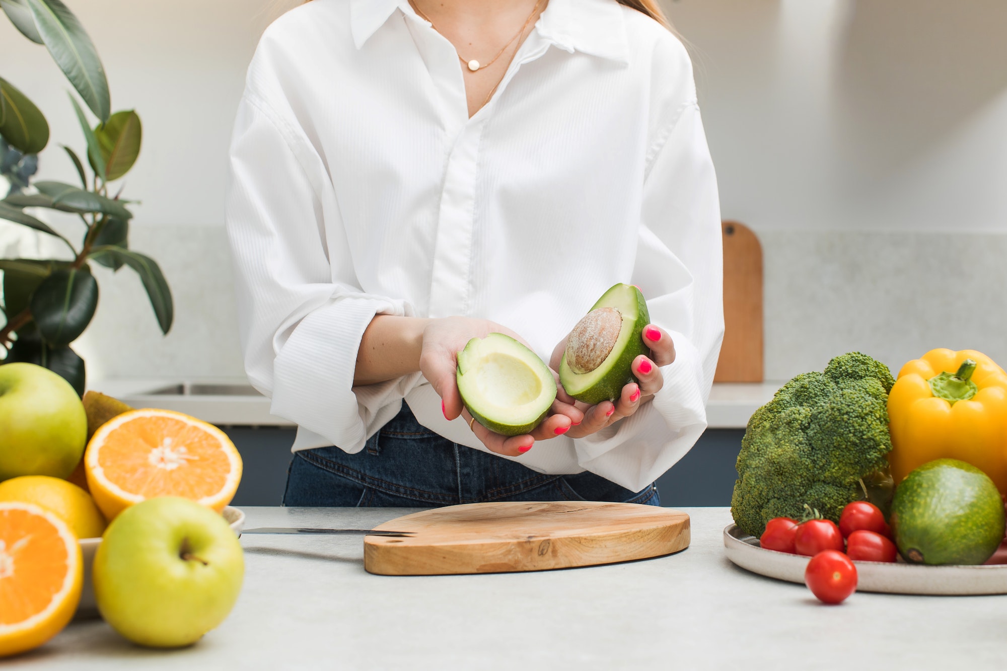a-woman-cut-a-ripe-avocado-and-holds-two-halves-in-her-hands-vegetarianism-